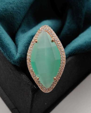 Luna Piena mint green AD ring resting on a teal velvet background