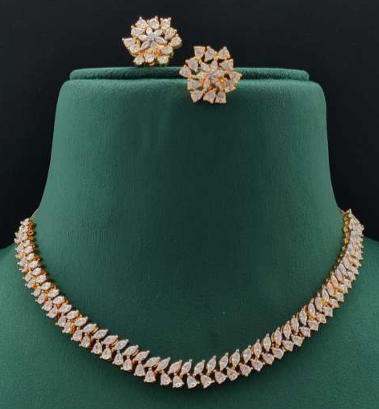 Elegant white gold-plated delicate AD necklace set with CZ stones and floral stud earrings displayed on green and black velvet busts – Lavish Jewels.