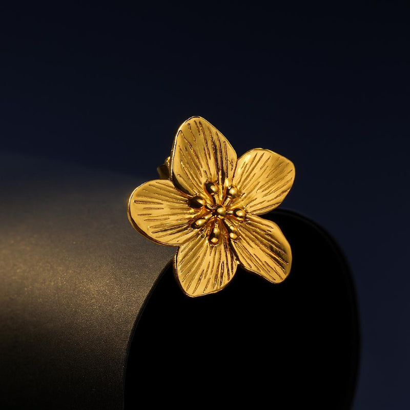 Gold flower-shaped earring on a black background