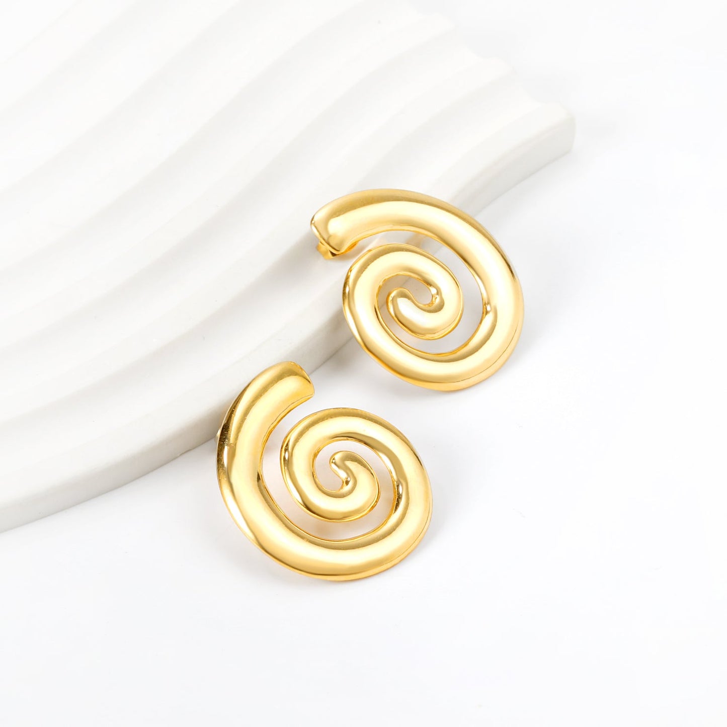 Orbit Stud Gold Earrings displayed on white surface – artistic spiral shape with high-polish gold finish