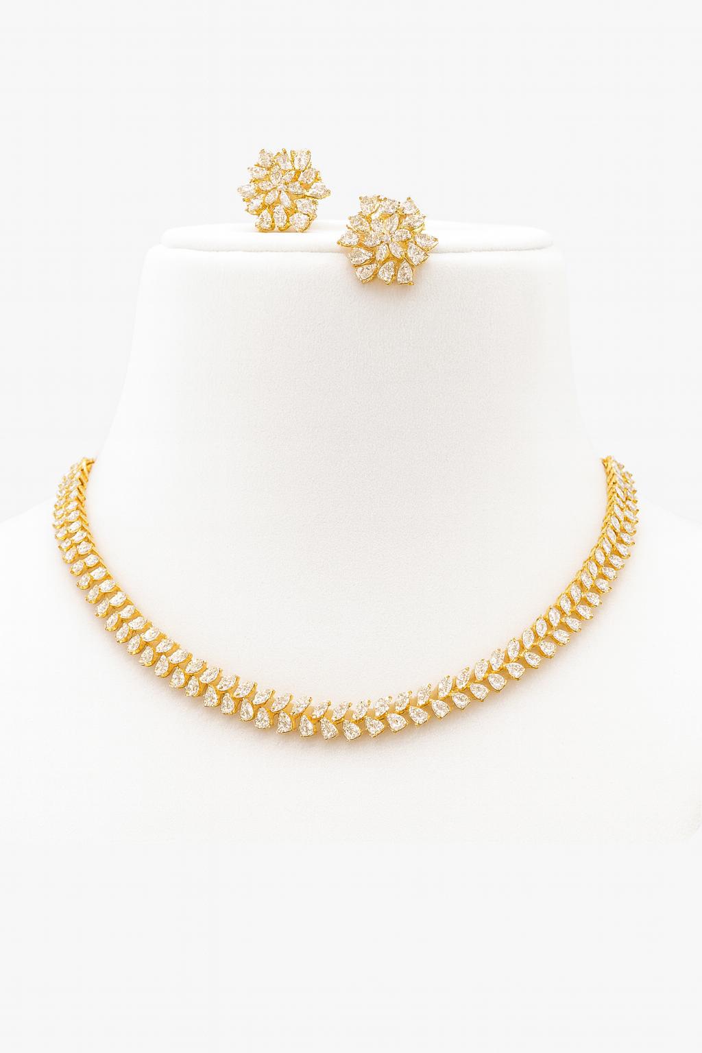 Elegant gold-plated delicate AD necklace set with CZ stones and floral stud earrings displayed on green and black velvet busts – Lavish Jewels.