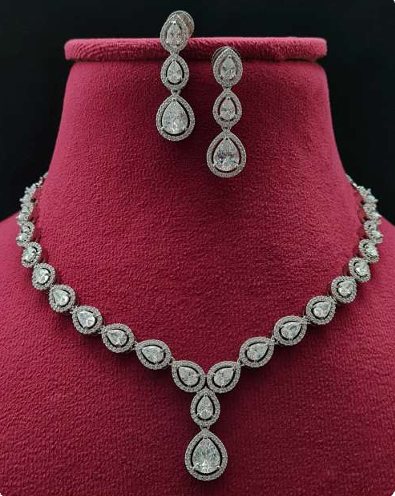 Bellissima Glow necklace set with teardrop CZ stones in white plating, paired with matching earrings, displayed on velvet and bust stand