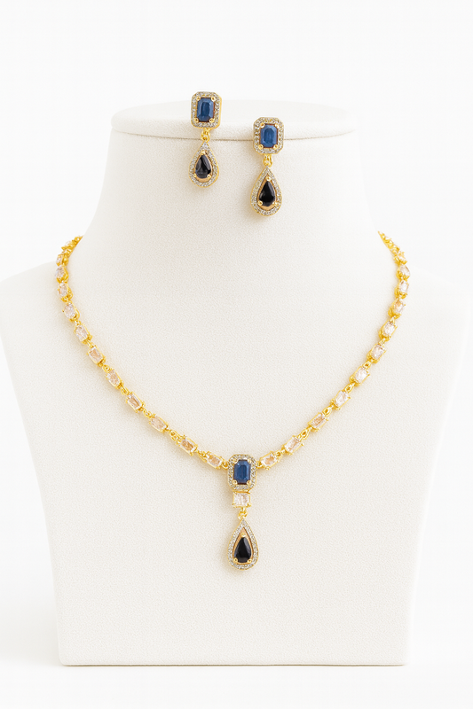 Aria Finezza necklace set displayed on a grey bust, featuring blue rectangular and teardrop stones with gold CZ detailing