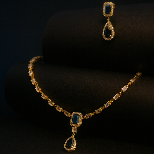 Aria Finezza necklace set displayed on a grey bust, featuring blue rectangular and teardrop stones with gold CZ detailing