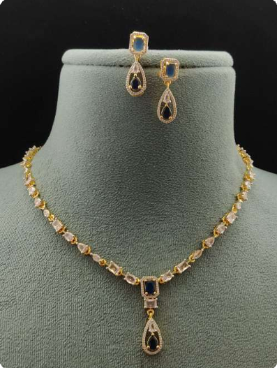 Aria Finezza necklace set displayed on a grey bust, featuring blue rectangular and teardrop stones with gold CZ detailing