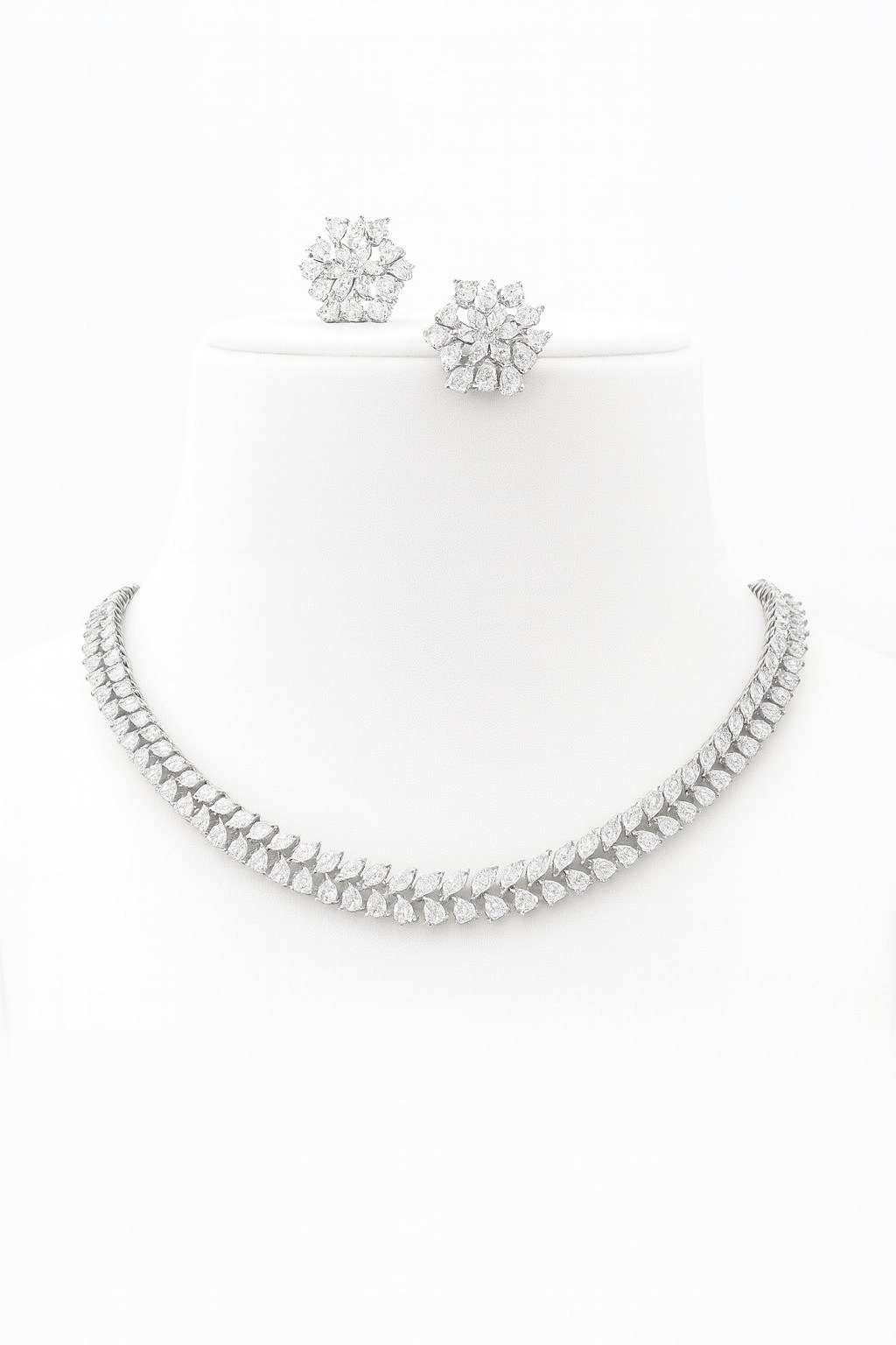 Elegant white gold-plated delicate AD necklace set with CZ stones and floral stud earrings displayed on green and black velvet busts – Lavish Jewels.