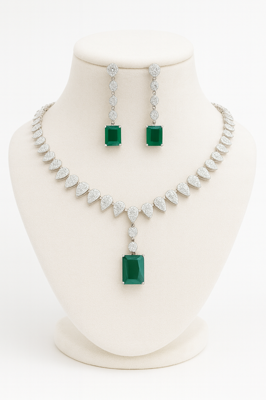 Jewelry set with necklace and earrings featuring emerald and diamond accents on a mannequin bust.