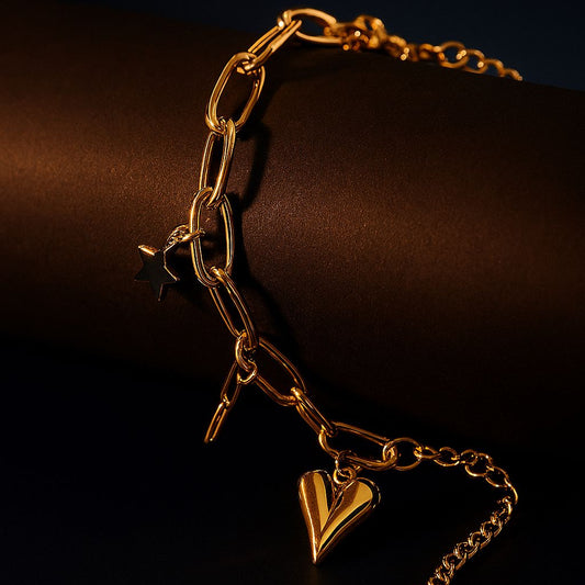 Gold chain bracelet with a heart-shaped charm on a dark background