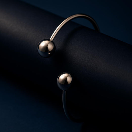 Silver bracelet with two spherical charms on a dark background