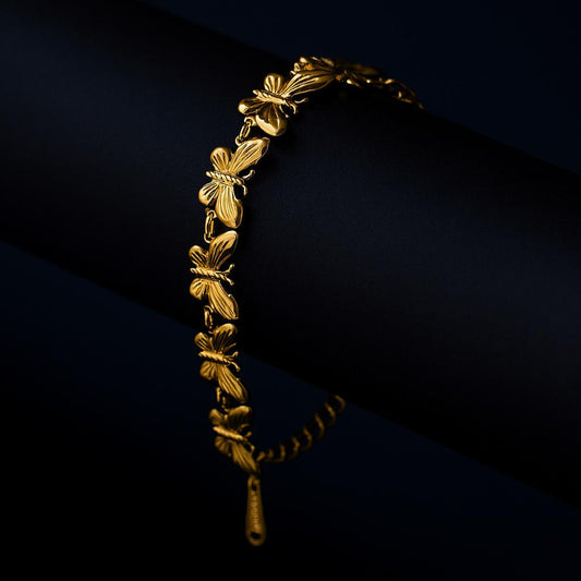 Gold bracelet with leaf designs on a dark background