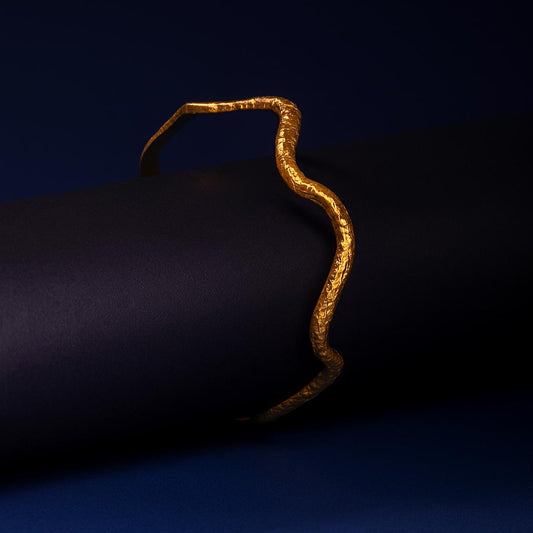Gold bracelet on a dark blue fabric background