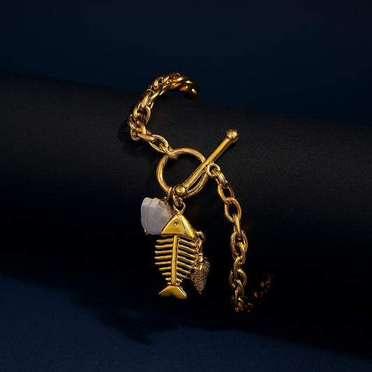 Gold bracelet with a fish-shaped charm on a dark background