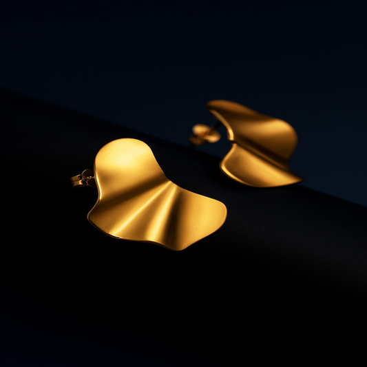 MUSE Arc Gold Stud Earrings – pair displayed on white textured surface with gold shine