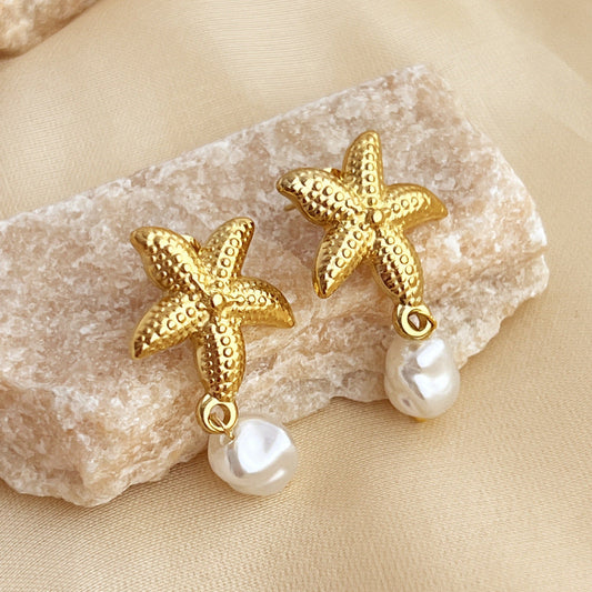 VEIL Stud Pearl Gold Earrings – starfish design with pearl drop in 18K PVD gold plated stainless steel on beige stone background