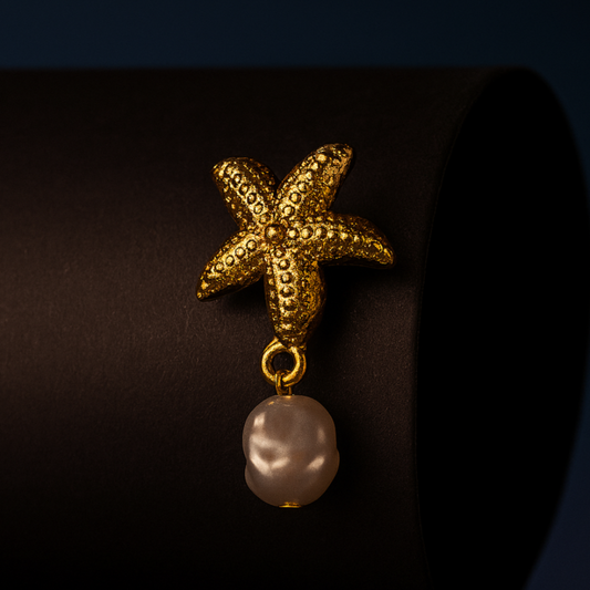 VEIL Stud Pearl Gold Earrings – starfish and shell designs with pearl drops in 18K PVD gold plated stainless steel on beige fabric background