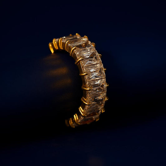 Gold ring with embedded diamonds on a dark background