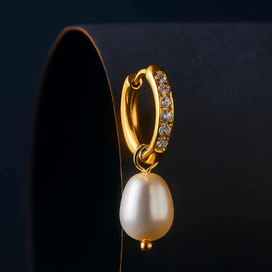 Gold hoop earring with a pearl drop on a dark background