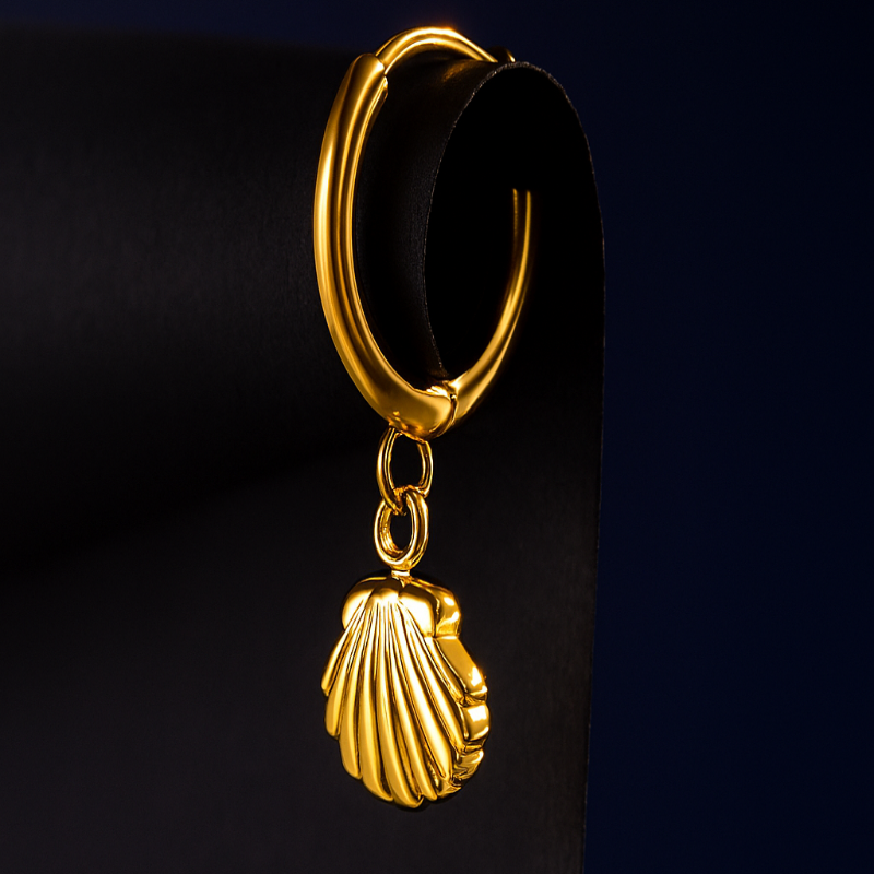 Gold hoop earring with a shell charm on a black background