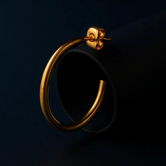 Gold hoop earring on a dark background
