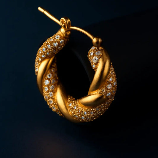 Gold hoop earring with embedded diamonds on a dark background