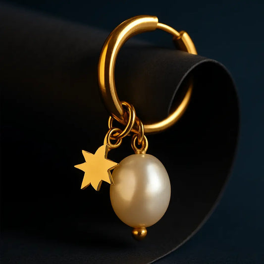 Gold keychain with a star and pearl charm on a dark background