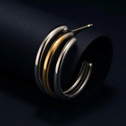 Three metallic rings in gold, silver, and bronze on a dark background