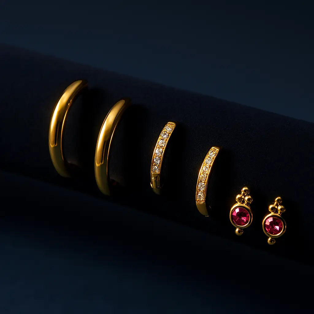Gold hoop earrings and pink gemstone earrings on a dark background