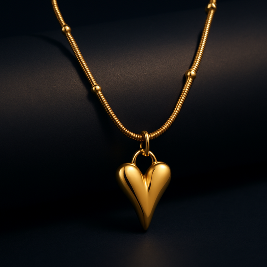"Zeal Elongated Heart Necklace in 18K PVD gold plated stainless steel on dark cylindrical surface with navy background"

