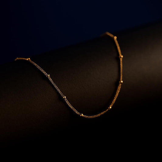 "Oceanic Glow Beaded Chain Necklace in 18K PVD gold plated stainless steel on dark cylindrical surface with navy background"