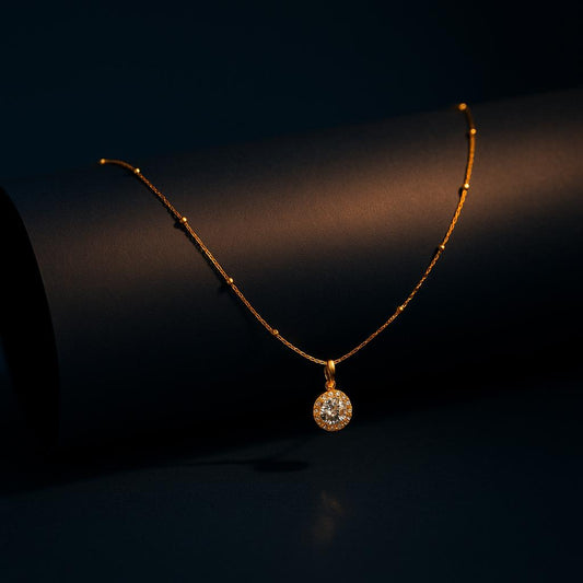 "Golden Wattle CZ Pendant Necklace in 18K PVD gold plated stainless steel on dark cylindrical surface with navy background"