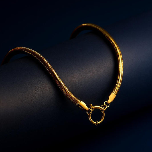 "Aurelia Snake Chain Choker with sailor clasp in 18K PVD gold plated stainless steel on dark cylindrical surface with navy background"