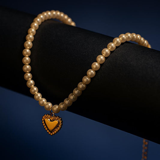Pearl bracelet with a gold heart charm on a black and blue gradient background