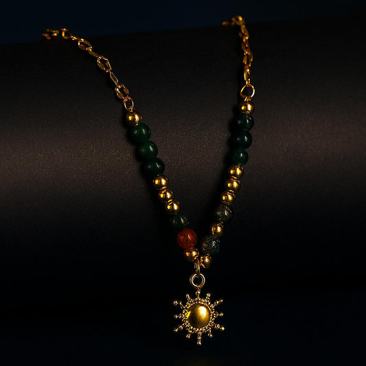 Necklace with green and gold beads and a star-shaped pendant on a dark background