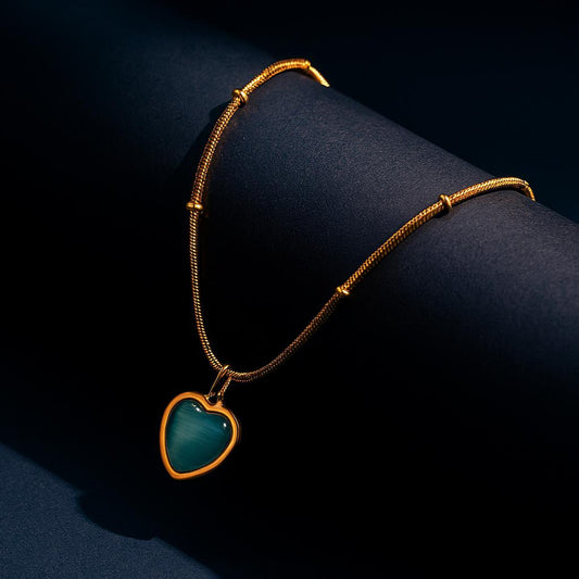 CALISTA Gold Necklace with heart-shaped blue stone pendant on dark background