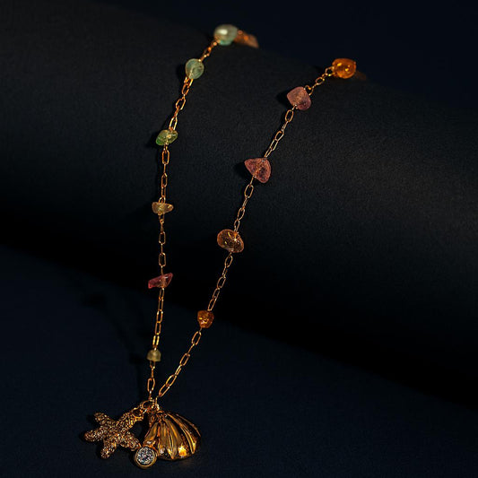 LUX AURA Gold Necklace with shell, starfish, and crystal charms – dark display background

