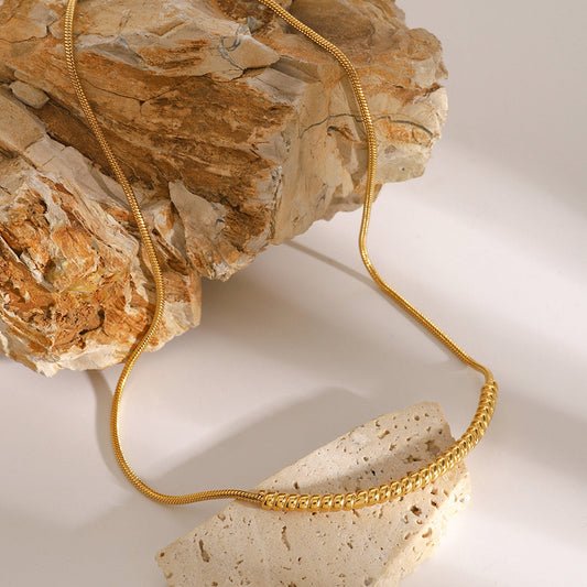 18K gold plated spiral twisted snake chain on natural stone background