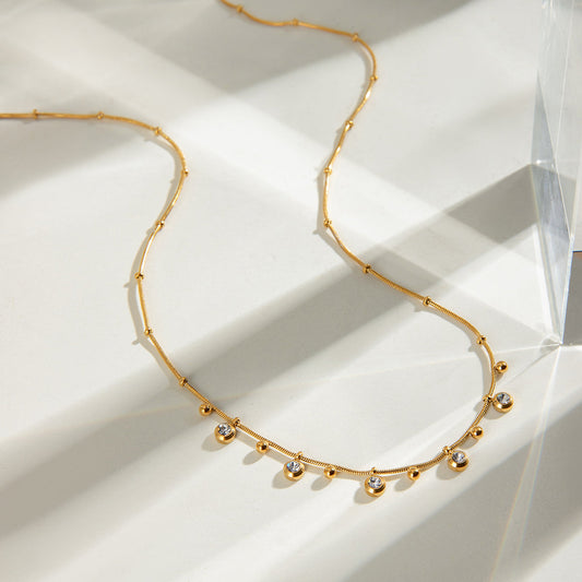Quest Gold Necklace – flat lay on light background showing gold chain with zircon charms.