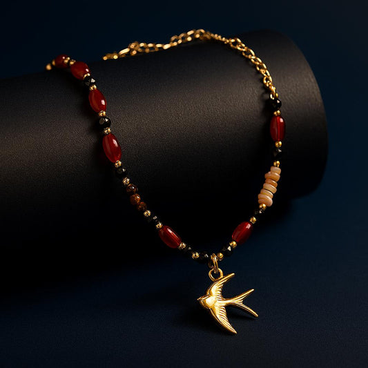 Onyx Gold Necklace with natural stones, crystals, and gold bird pendant – styled on dark background