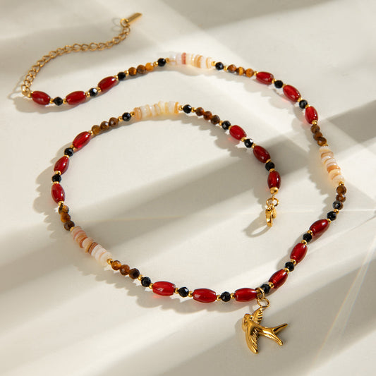 Onyx Gold Necklace with natural stones, crystals, and gold bird pendant – flat lay