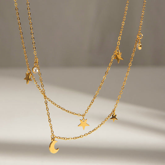 Kismet Gold Double Layer Necklace with star, moon & crystal charms on a light background