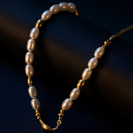 Luxury pearl and gold necklace displayed on dark cylindrical surface