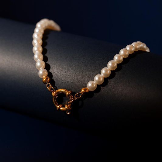 FLAIR Gold Necklace displayed on dark cylindrical surface showcasing pearl luster