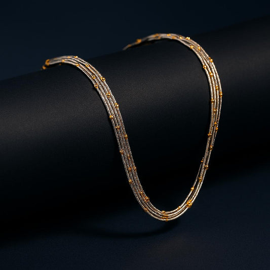 Dusk Gold Necklace – elegant gold and silver snake chain with bead details displayed on dark cylindrical surface