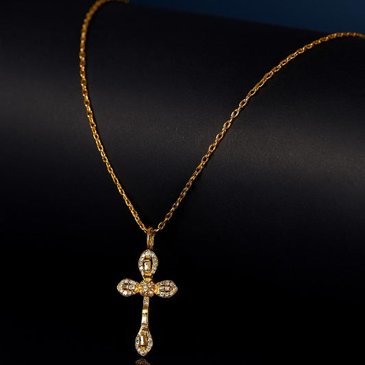 Talia Gold Necklace – crystal cross pendant displayed on gold chain over black matte roll with dark background