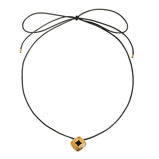 Rune Gold Necklace – black cord with gold geometric pendant and black enamel on white background