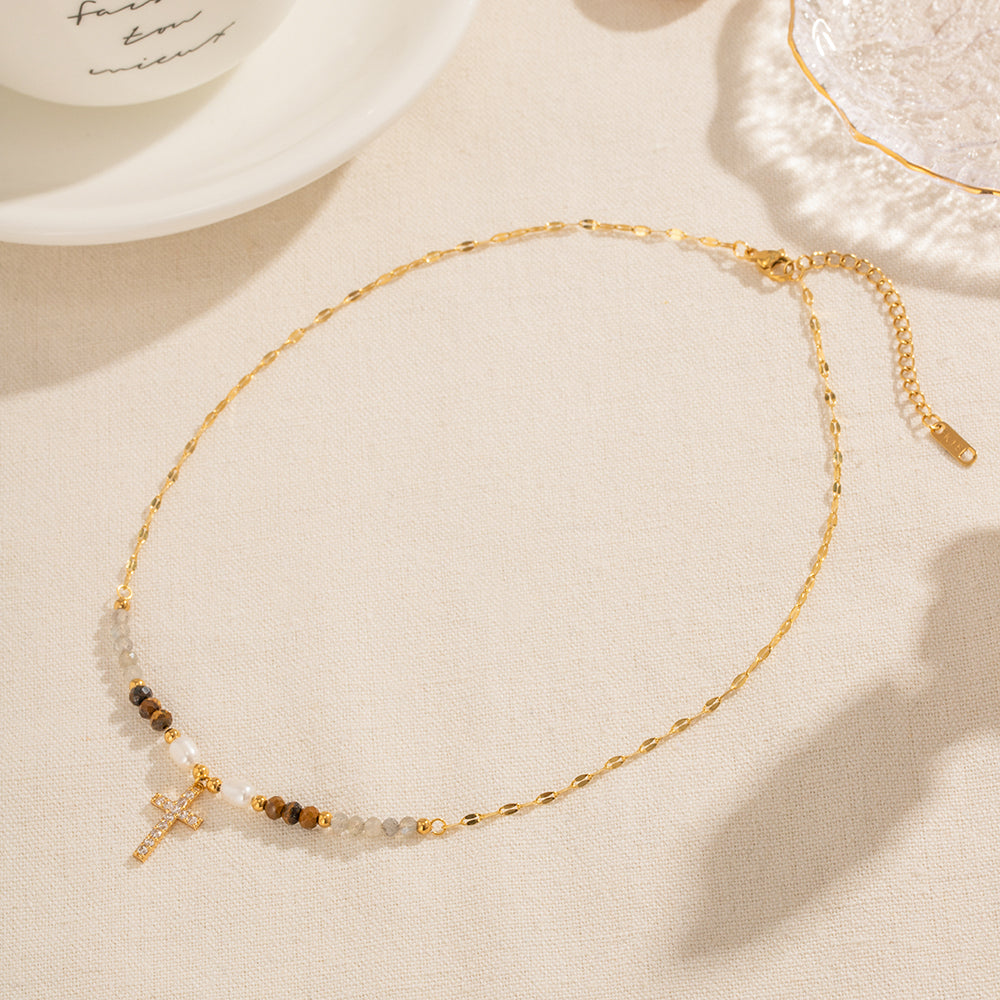 Lyric Gold Necklace – gemstone beaded chain with zirconia cross pendant on light fabric background