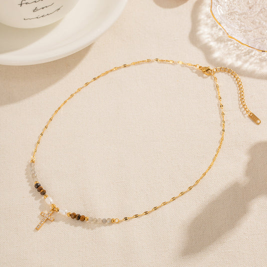 Lyric Gold Necklace – gemstone beaded chain with zirconia cross pendant on light fabric background