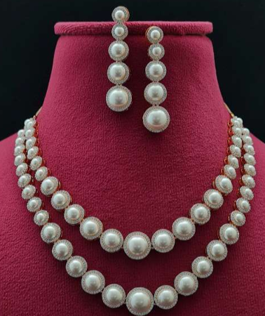 Sole Dorato layered pearl necklace set on red velvet bust with matching drop earrings