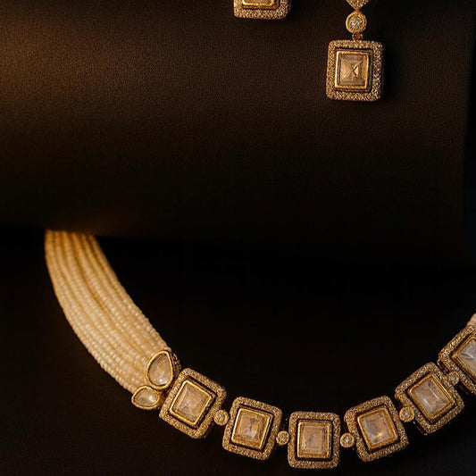 Dolce kundan necklace and earrings laid flat on dark cylindrical surface with warm lighting